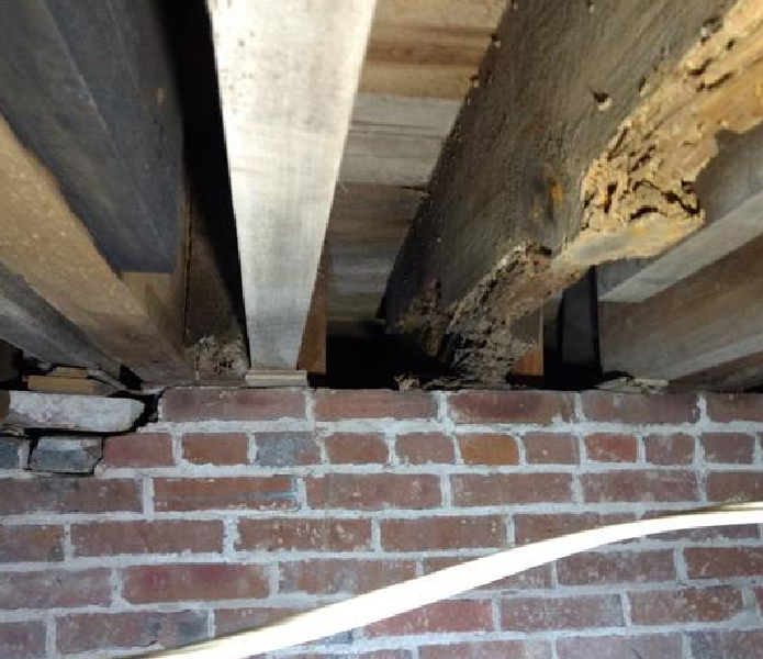 A brick wall with exposed wood beams and a ceiling.